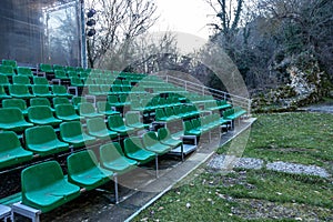 Empty old plastic chairs in the stands of the summer theater. Many empty seats for spectators in the stands of the amphitheater.