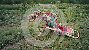 Empty old stroller in a field against the sky, an inverted baby carriage without a child