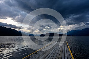 An empty old wooden dock on Harrison Lake leads into the coming storm