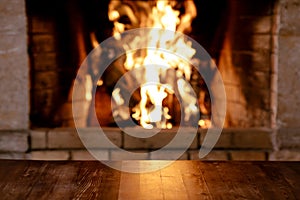 Empty old wooden table against burning wood in the fireplace