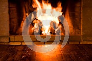 Empty old wooden table against burning wood in the fireplace