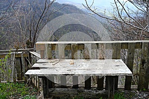 Empty old wooden table in front of a blurry view of forested mountains. Big plan. For the background.