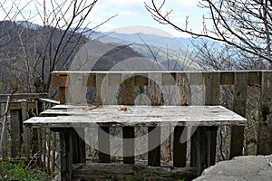 Empty old wooden table in front of a blurry view of forested mountains. Big plan. For the background. Can be used for