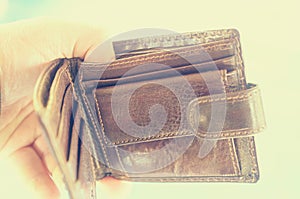 Empty open brown purse in one hand.