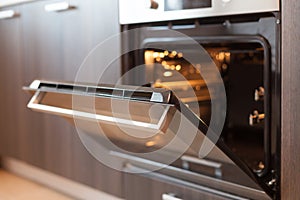 Empty open electric oven with hot air ventilation. New oven. Door is open and light is on.