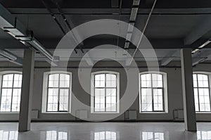 Empty open space in old factory building with columns, large windows and pipes under the beton ceiling