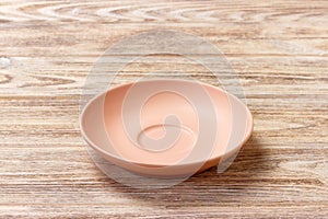 Empty orange matte plate on wooden background. Perspective view