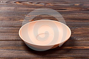 Empty orange matte plate on wooden background. Perspective view