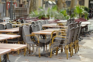 An empty outdoor cafe in a European city on an autumn day. Chairs and tables are stacked. Fallen leaves are lying on the ground.