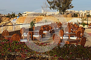 Empty outdoor cafe terrace with wooden tables and chairs. Stunning landscape during sunny day. Summer vacation concept