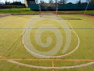 Empty outdoor handball playground, plastic hairy green surface on ground and white blue bounds lines.