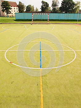 Empty outdoor handball playground, plastic light green surface on ground. Empty gate.