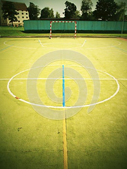 Empty outdoor handball playground, plastic light green surface on ground and white blue bounds lines.