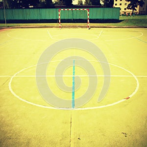 Empty outdoor handball playground, plastic light green surface on ground and white blue bounds lines.