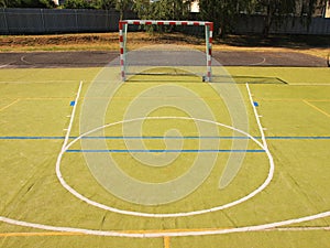 Empty outdoor handball playground, plastic light green surface on ground and white blue lines.
