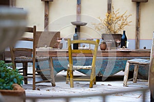 Empty outdoor vintage restaurant in winter. Wooden aged table and chairs with bottles and glasses. desolation concept
