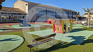 Empty outdoors schoolyard school playground preschool building exterior with little house and bench