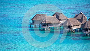 Empty overwater villas sitting in the middle of the crystal clear exotic sea.