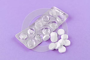 Empty pack with white pills packed in blister with copy space on purple background. Focus on foreground, soft bokeh