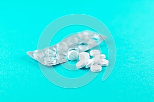 Empty pack with white pills packed in blister with copy space on turquoise background. Focus on foreground, soft bokeh. Pharmacy d