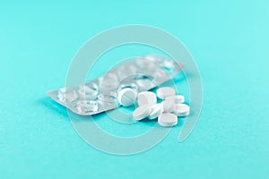 Empty pack with white pills packed in blister with copy space on turquoise background. Focus on foreground, soft bokeh. Pharmacy d