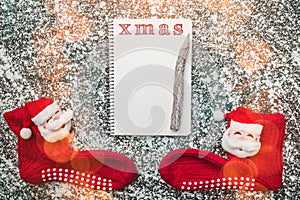 Empty page of spiral notebook and Christmas red stockings on a snow background