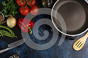 Empty pan on marble dark blue table with variety of ingredients background. Backstage of cooking spaghetti pasta. Concept of
