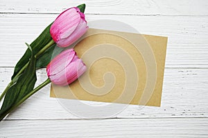 Empty paper card with pink tulip flower flat lay on wooden background