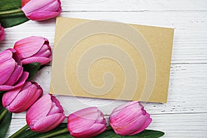 Empty paper card with pink tulip flower flat lay on wooden background