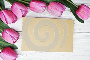 Empty paper card with pink tulip flower flat lay on wooden background