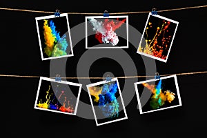 Empty paper cards attached with colorful clothespins on linen rope on a black background, blank templates concept office and photo