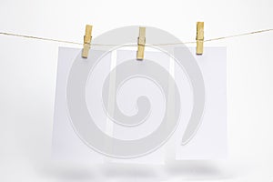 Empty paper frames that hang on a rope with clothespins and on white background with selective focus. Blank flyers on rope. Mockup