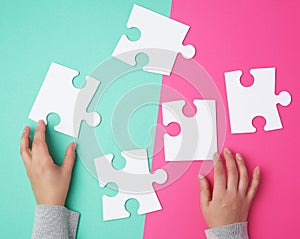 Empty paper white pieces of puzzles in female hands, puzzle connected