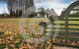 Empty park bench seen in a public park, close to a football pitch, seen in winter.