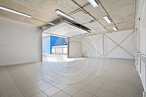 Empty parking garage, warehouse interior with large white gates and gray tile floor