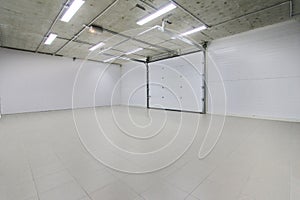 Empty parking garage, warehouse interior with large white gates and gray tile floor