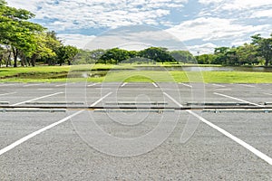 Empty parking lot against green lawn