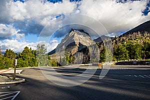 An empty parking lot in the Glacier National Park, with heavy clouds touching the mountain peak