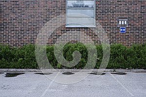 Empty parking near red brick wall and green bushes, deadpan photodraphy photo