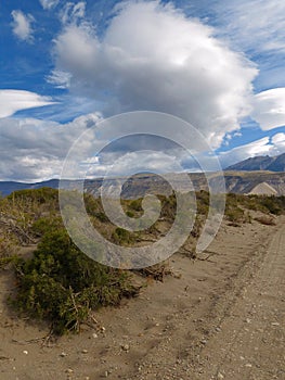 Empty Path in the Wasteland. A Sunny Sky Full of Big Fluffy Clouds.