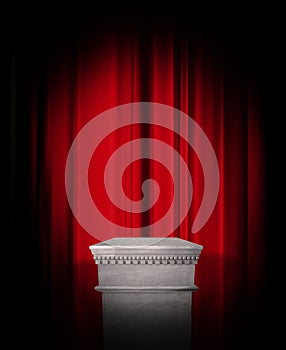 Empty pedestal display on red curtain