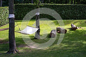 Empty pendant hammock in trees on green lawn in park.