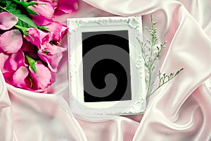 the Empty photo frame with a bouquet sweet pink roses petal on