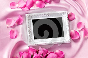 Empty photo frame with a bouquet sweet pink roses petal on sof