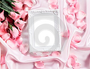 Empty photo frame with a bouquet sweet pink roses petal on soft pink silk fabric , romance and love card concept