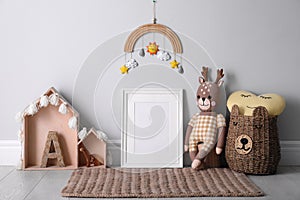 Empty photo frame and cute toys near wall in baby room. Interior design