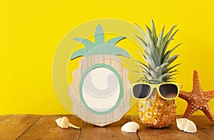 Empty photo frame and funny pineapple with sunglasses. For photography and scrapbook montage