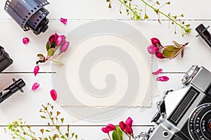 Empty photo frame, retro camera, photo film rolls and flowers