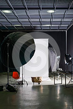 Empty photo studio with modern interior and lighting equipment. Preparation for studio shooting: empty chair and studio lighting.