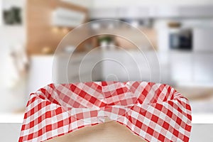 Empty picnic basket. Close-up of a empty straw basket with a checkered red napkin on table over blurred kitchen background. For